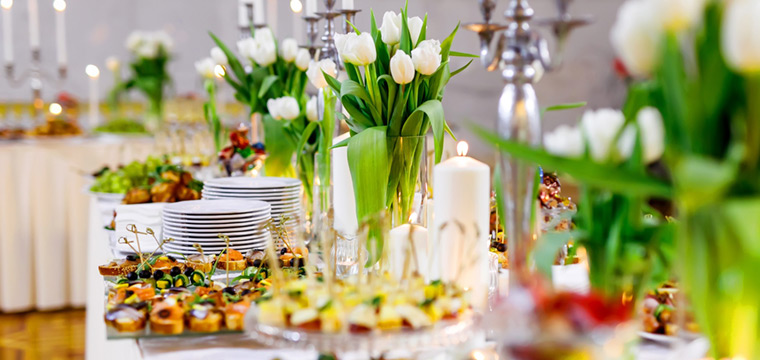 Canapés, platos y decoración con flores en la mesa de catering