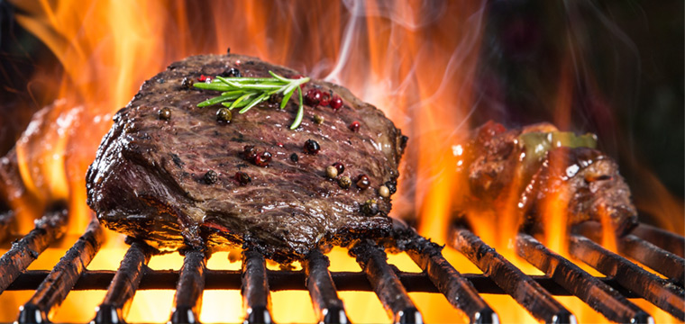 Carne asándose en una parrilla con fuego para un catering